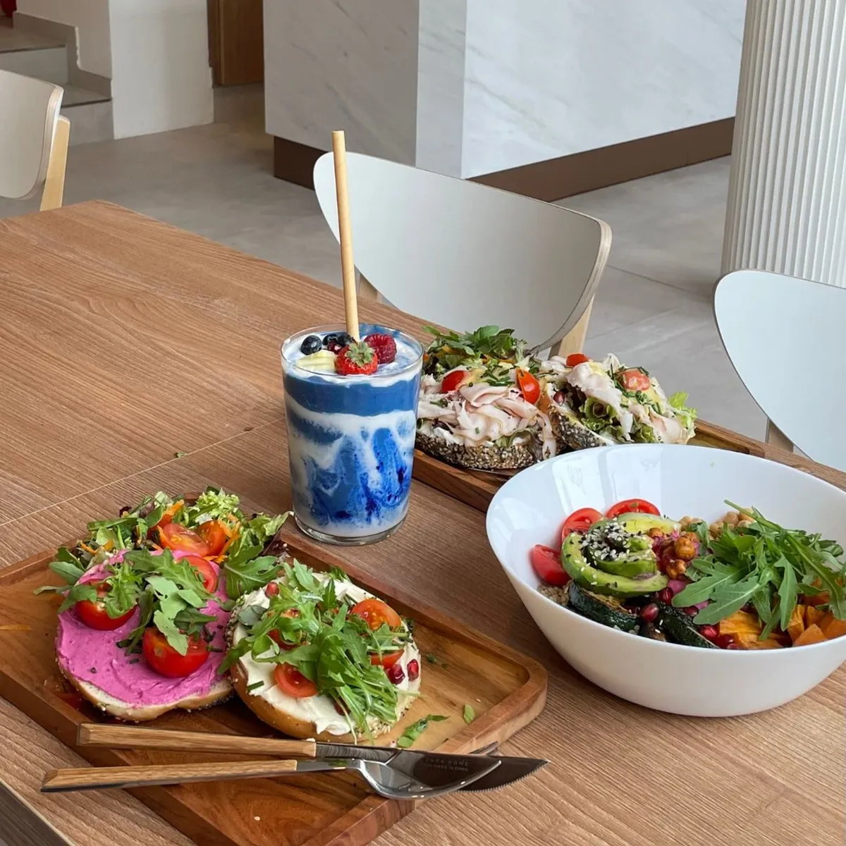 Toasts mit Rote-Bete-Creme, eine Bowl und ein Smoothie auf einem Holztisch