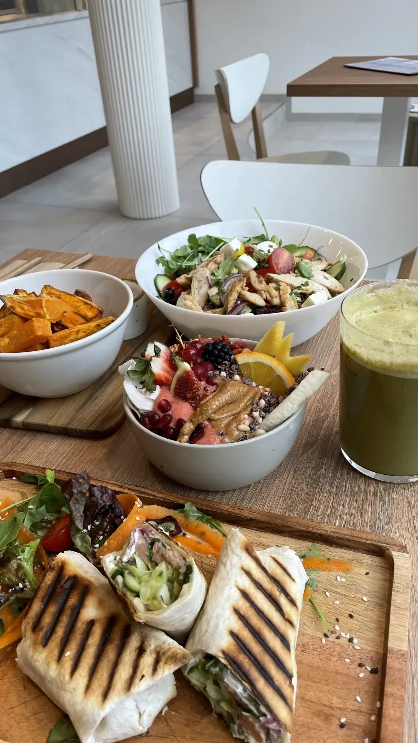 Gegrillte Wraps auf Holzbrett, Süßkartoffel-Pommes, Bowls und grüner Saft